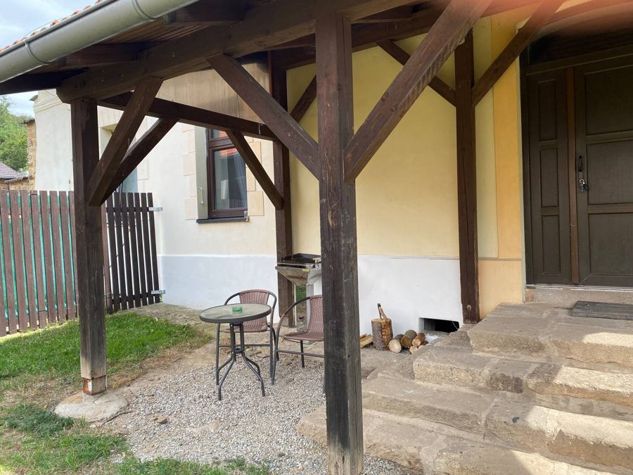 Kryté zápraží s dřevěnými trámy, stolkem a židlemi